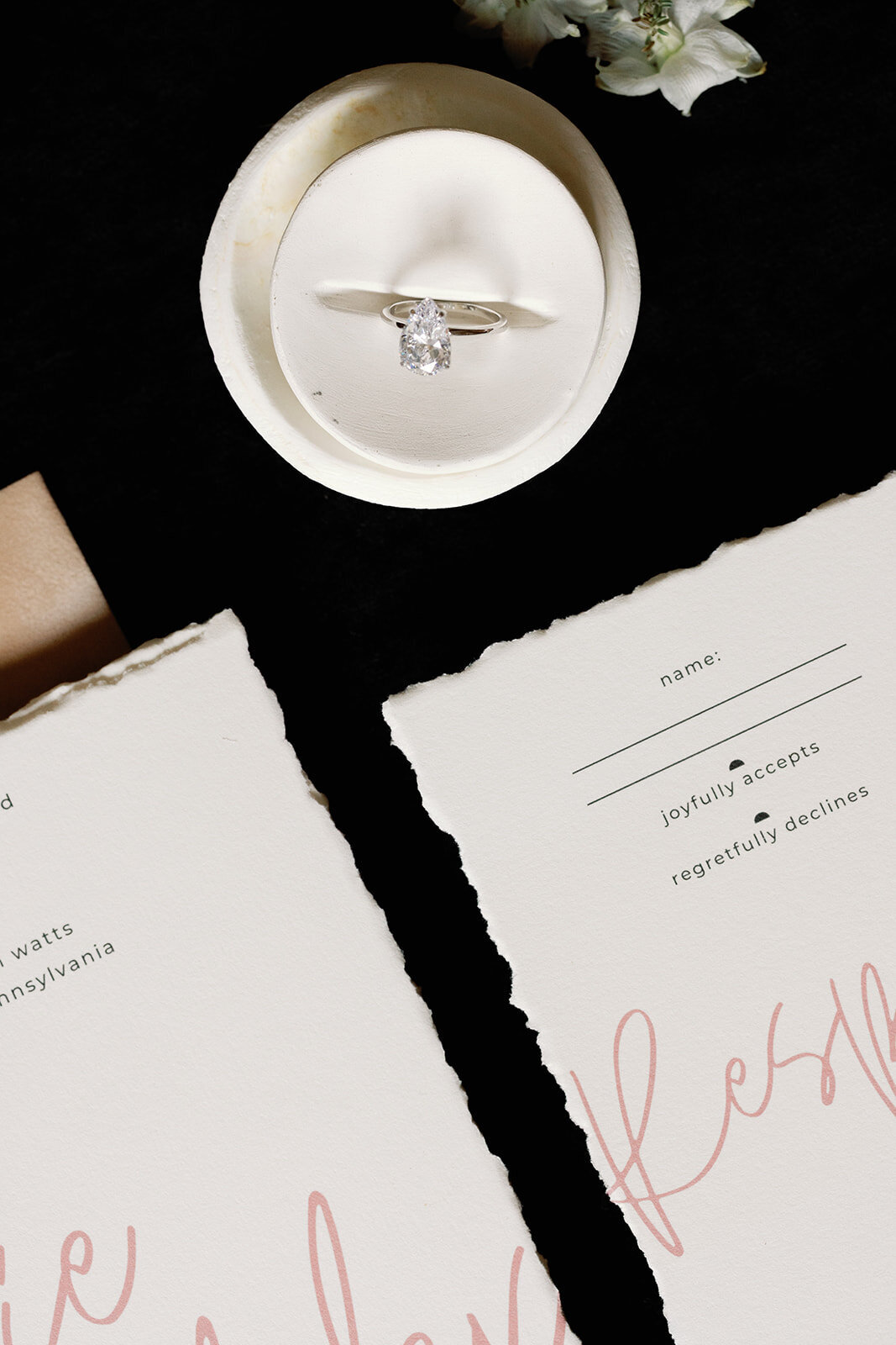 Close-up of wedding stationery and a diamond ring in a ring box