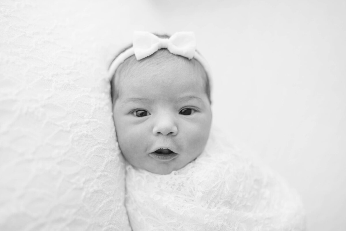 newborn baby girl looking with eyes open in a stunning black and white timeless portrait near oklahoma city