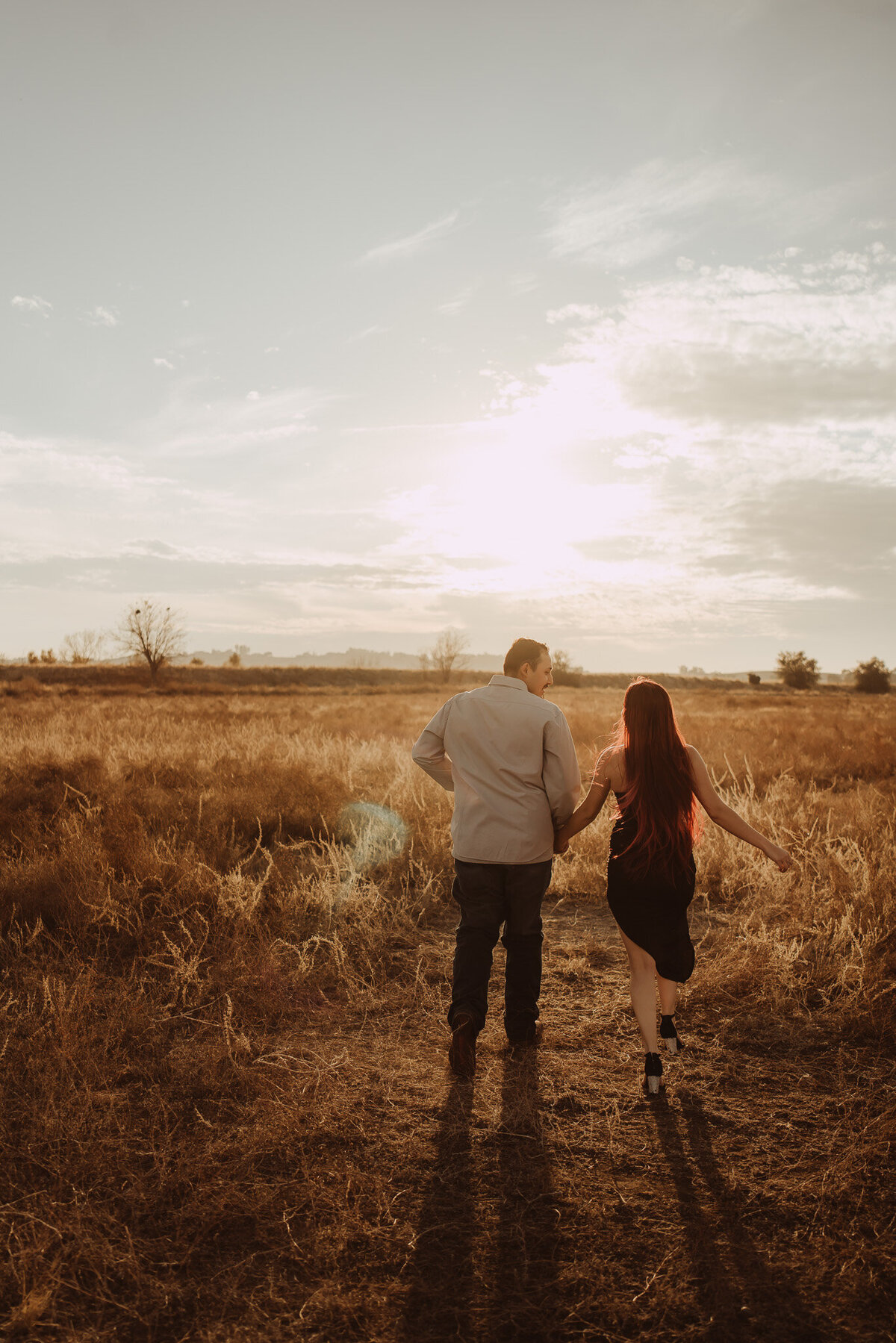 a young couple holding hands, running to the sunset ahead man looking over at the woman