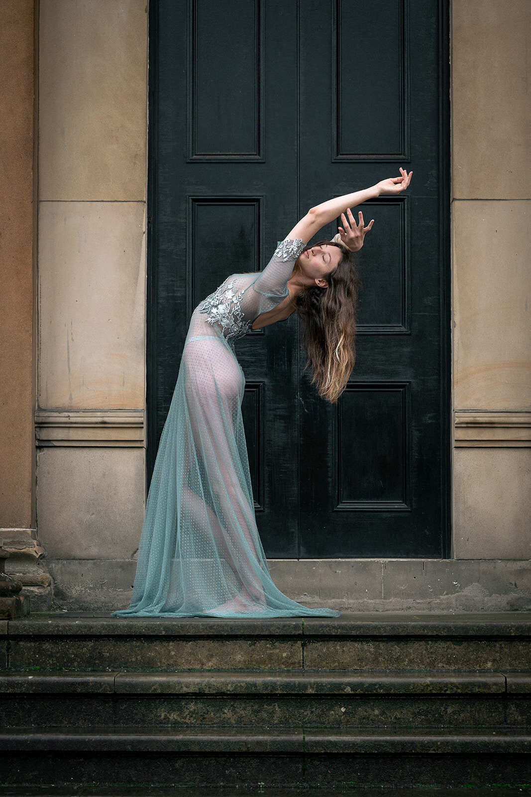 A bride stretches back in a bespoke blue wedding gown