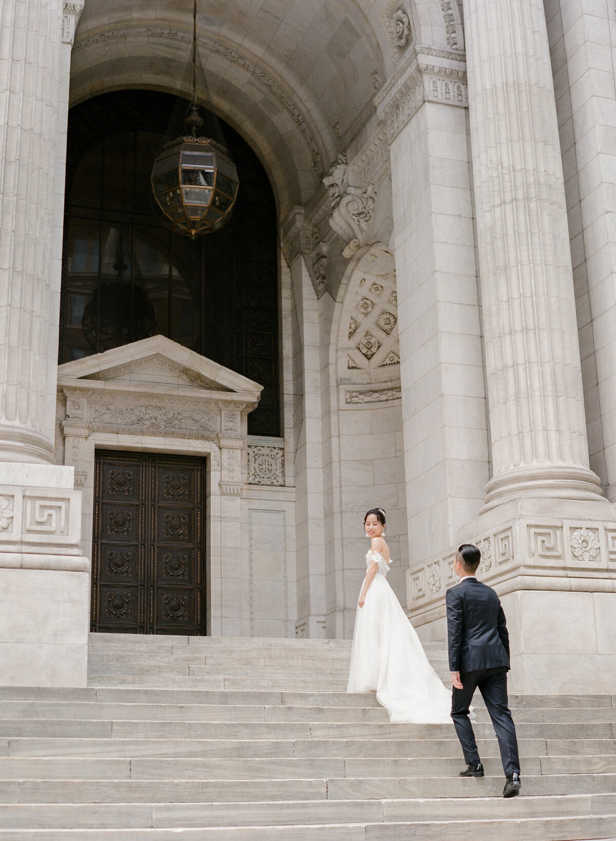 Bride and groom walking up front steps at New York Public Library