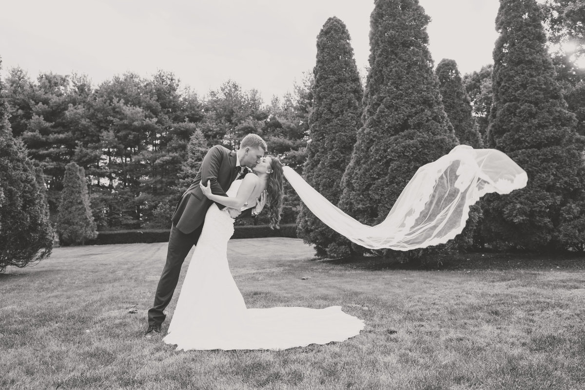 black and white photo of bride and groom shot outside with veil flowing from wedding reception at The Carltun