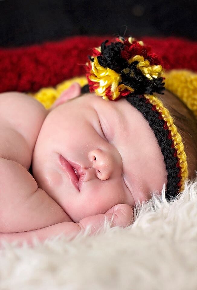 My daughter as a newborn with a German flag blanket behind her and a matching headband on her head.