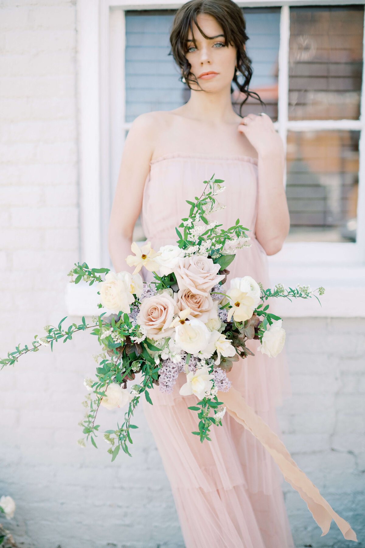 woman holding bouquet of blush, lavender, ivory florals and greenery