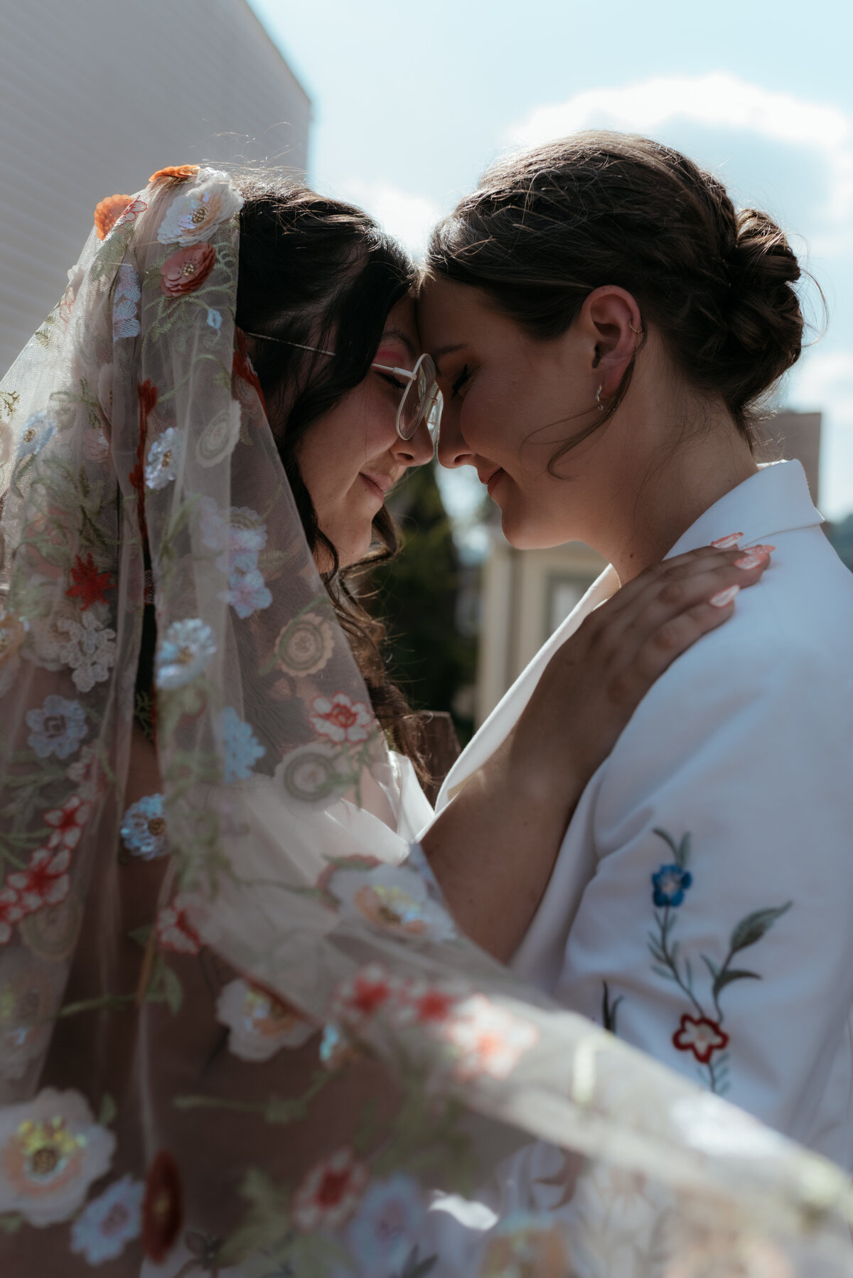 A bride with a Madison Chamberlain veil touches her forehead to her wife's during wedding portraits at Javo Studios in Pittsburgh.