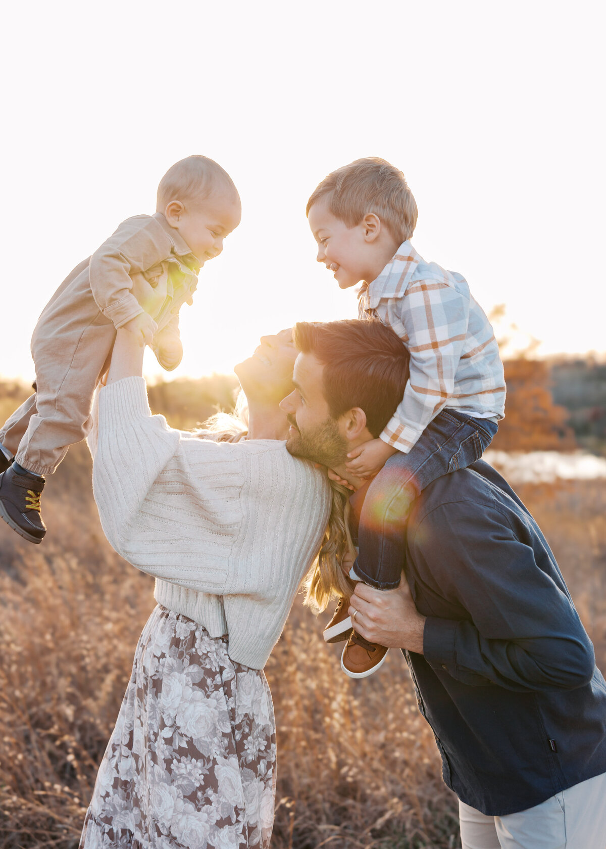 family of four play during golden hour for their family photography session at richmond nature center in bloomington, mn.