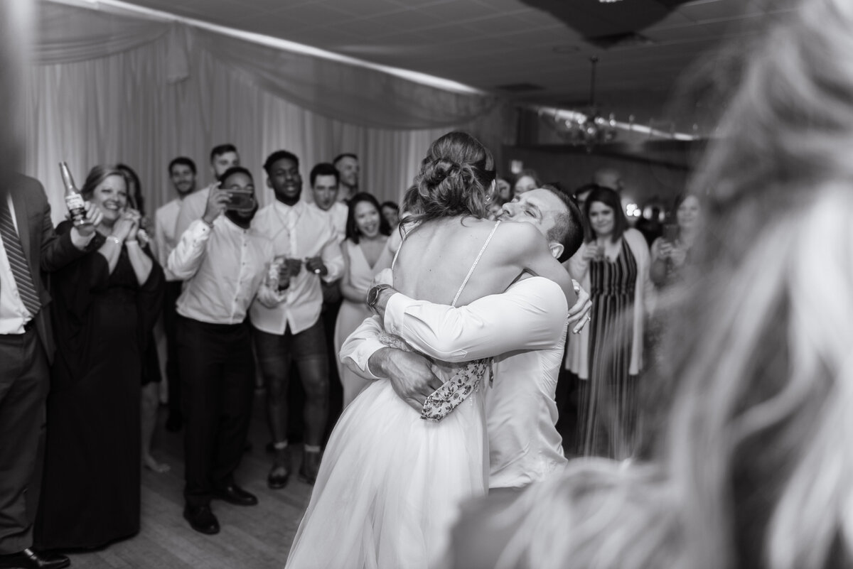 extremely happy couple hug one another in front of all family and guests at their wedding reception. Cleveland, Ohio. Photographed by Aaron Aldhizer
