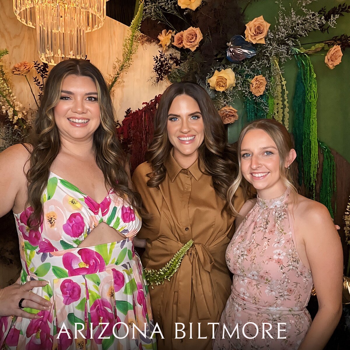 Three women posing in front of a luxury floral photo booth backdrop designed by Bloom & Blueprint at the Arizona Biltmore—captured by MISGIF Photo Booth for a high-end corporate event in Phoenix, Arizona.