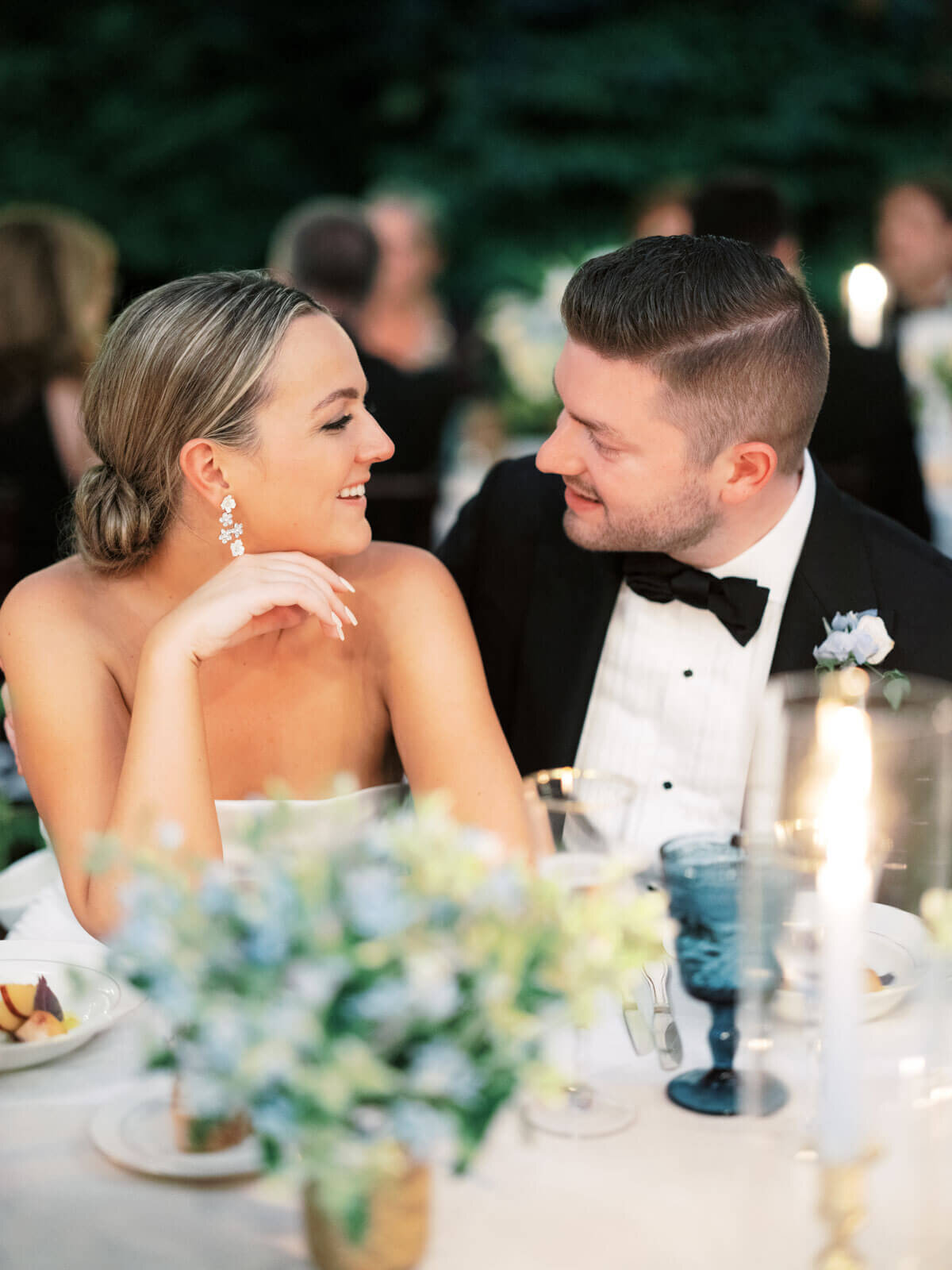 The bride and the groom are happily staring at each other while seated at the elegant wedding reception. Image by Jenny Fu Studio