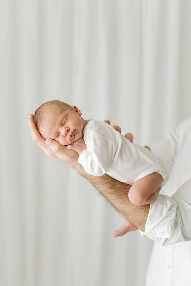 Father holds his newborn baby in his arms during a newborn studio shoot near Bristol