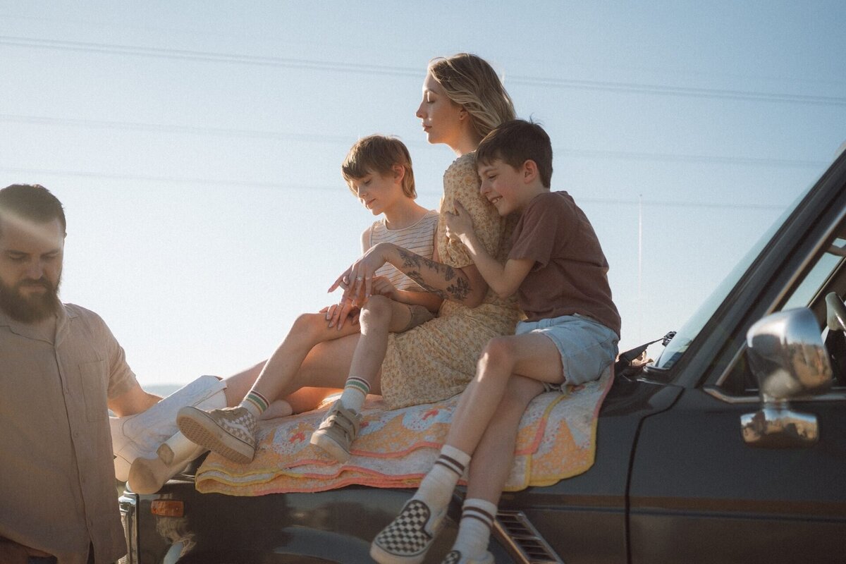 female sitting on top of car with two boys in taos new mexico