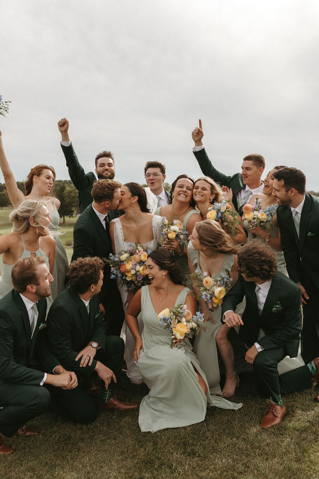 Bride and groom sharing a kiss as their bridal party cheers them on during a wedding celebration