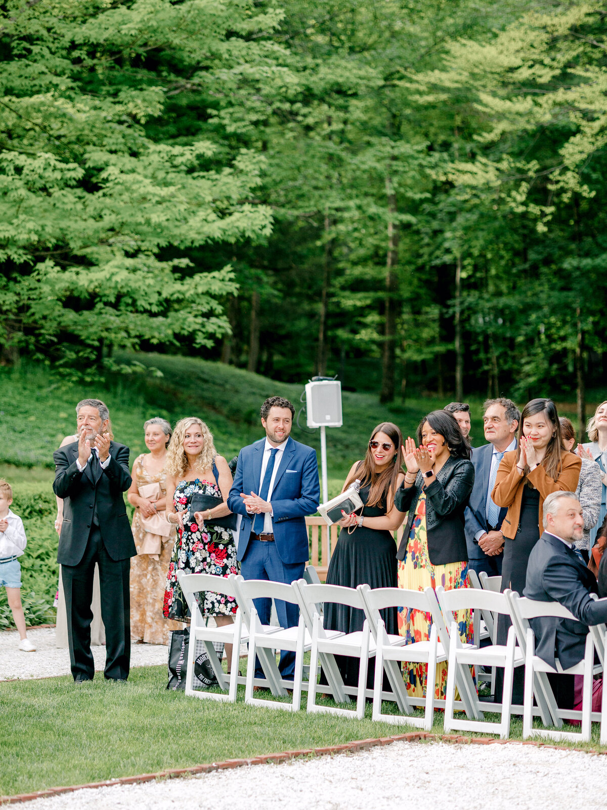 Wedding guests stand and clap as they watch wedding ceremony recessional