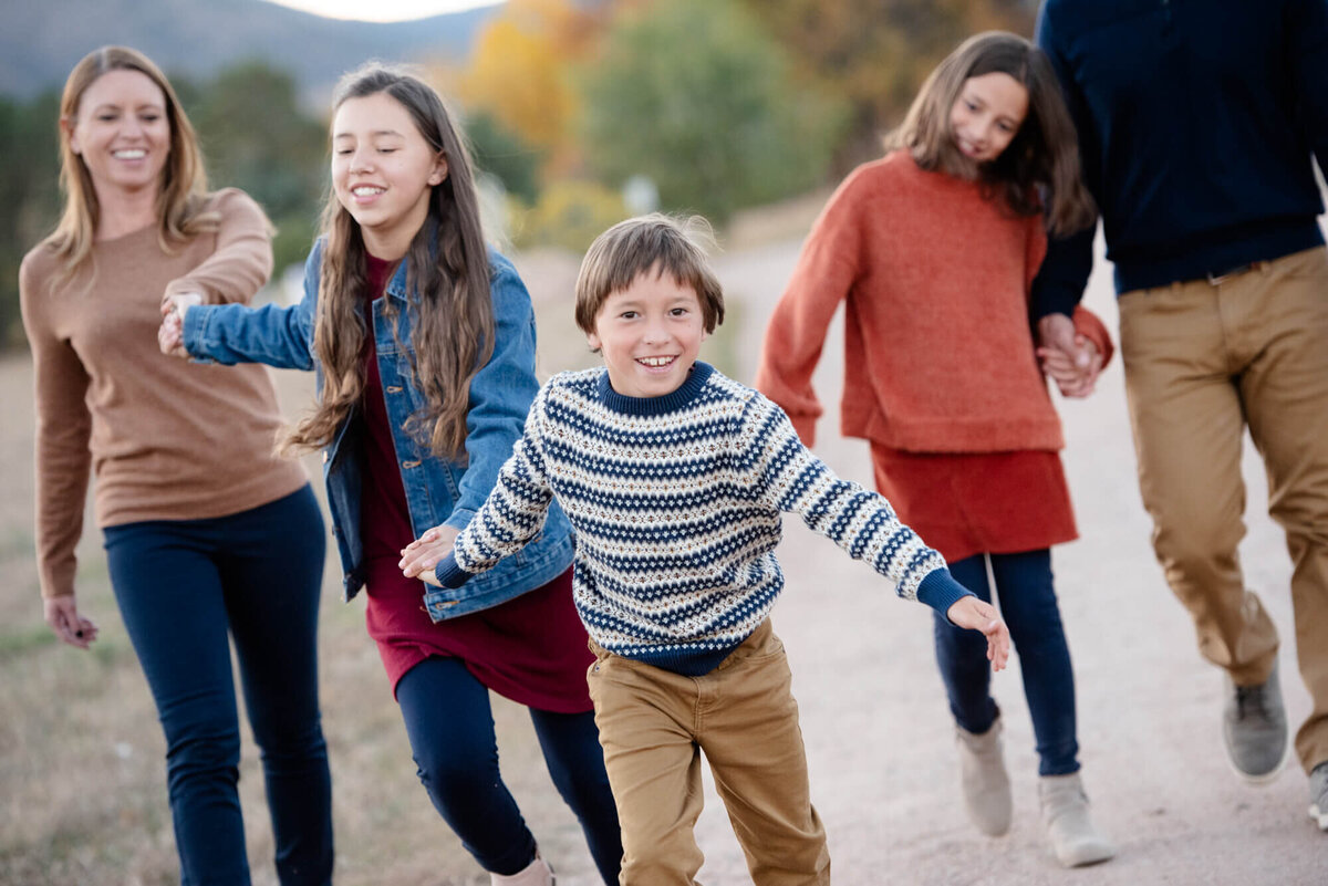 A young boy runs and pulls his family along a park trail