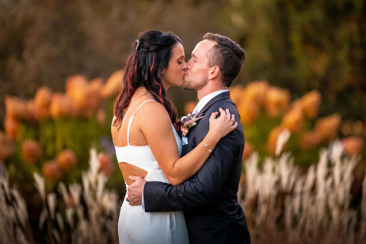 Bride and groom share their first kiss at sunset in the botanical gardens of Phipps Conservatory. Captured by Pittsburgh Wedding Photographer Michael Fricke Photography.