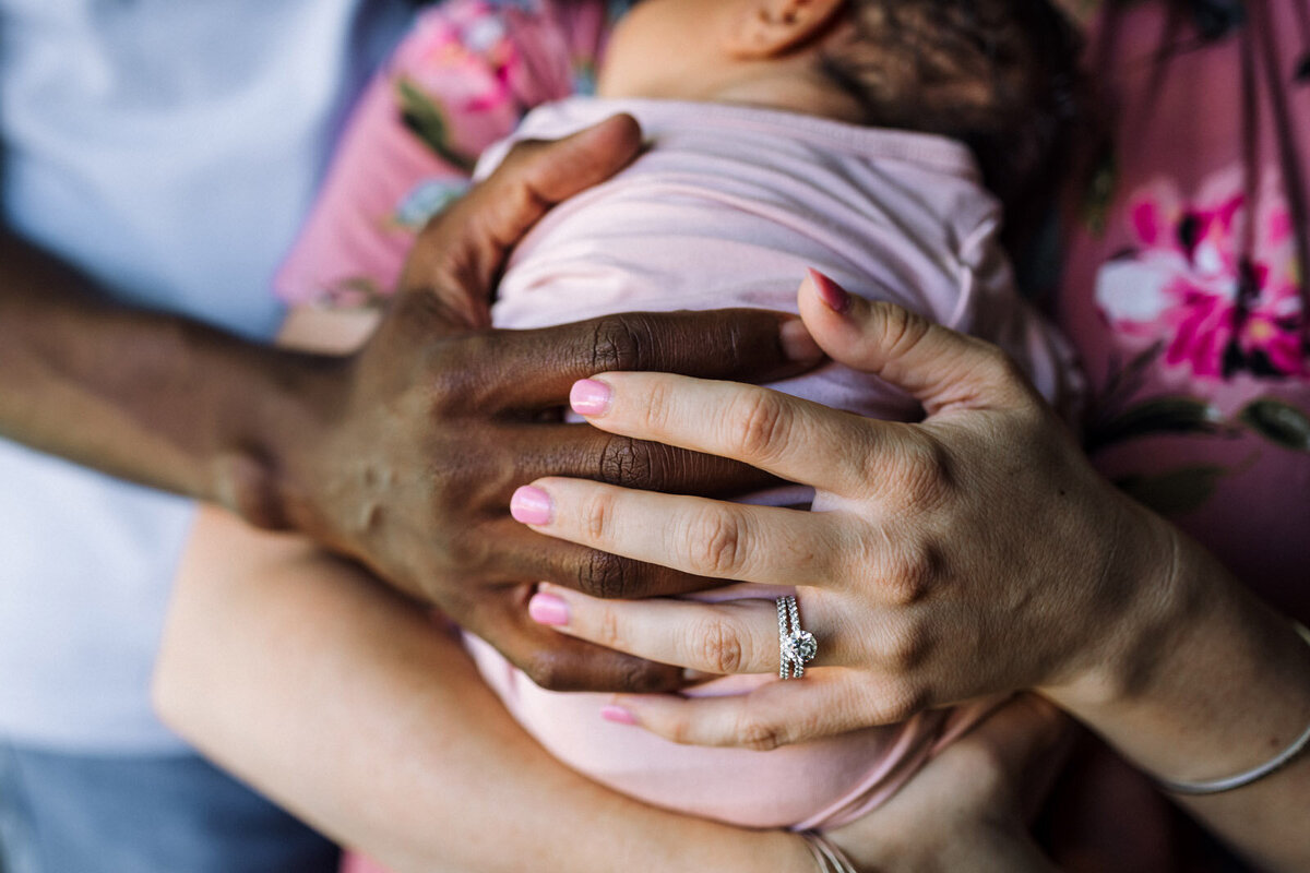 parent-hands-holding-newborn