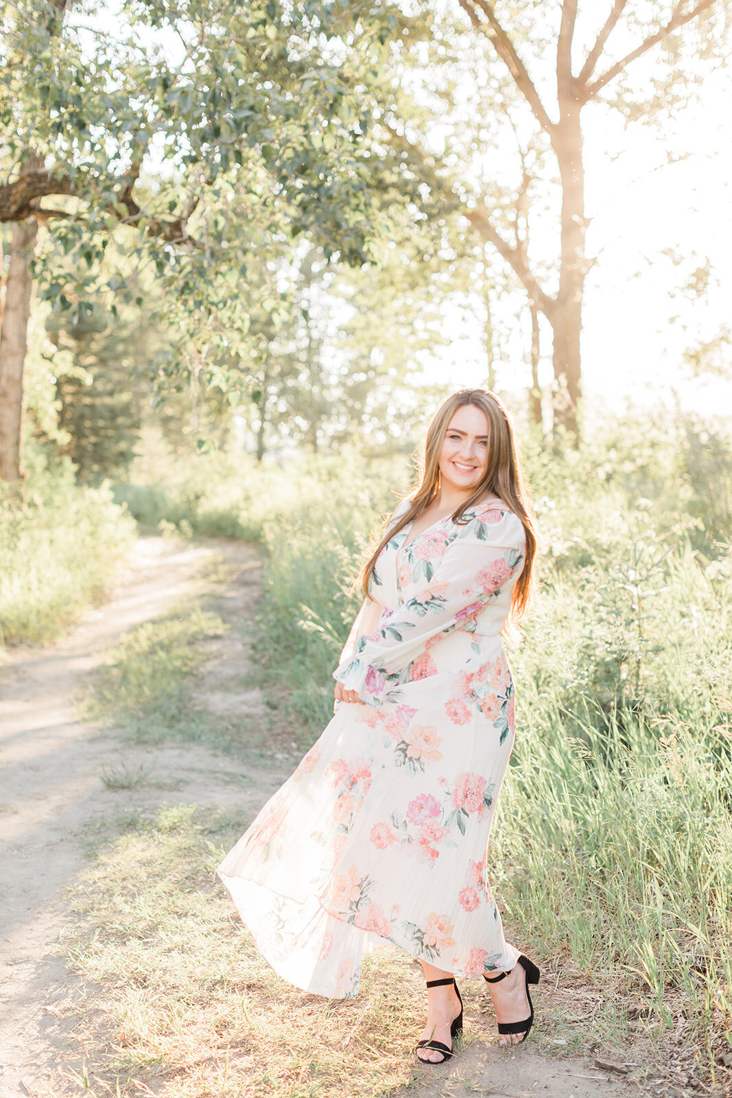 Woman in flowy floral dress in a grassy park in Calgary, AB