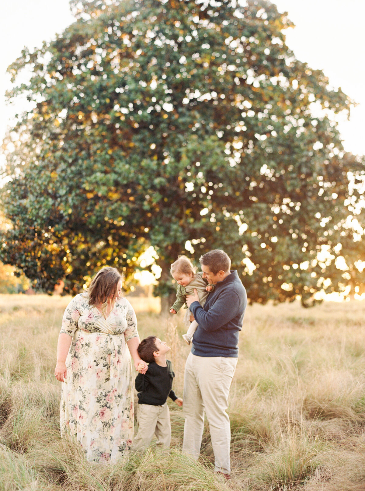 Family stands in front of a giant magnolia tree at the NC Museum of Art. Image by Raleigh maternity photographer A.J. Dunlap Photography.