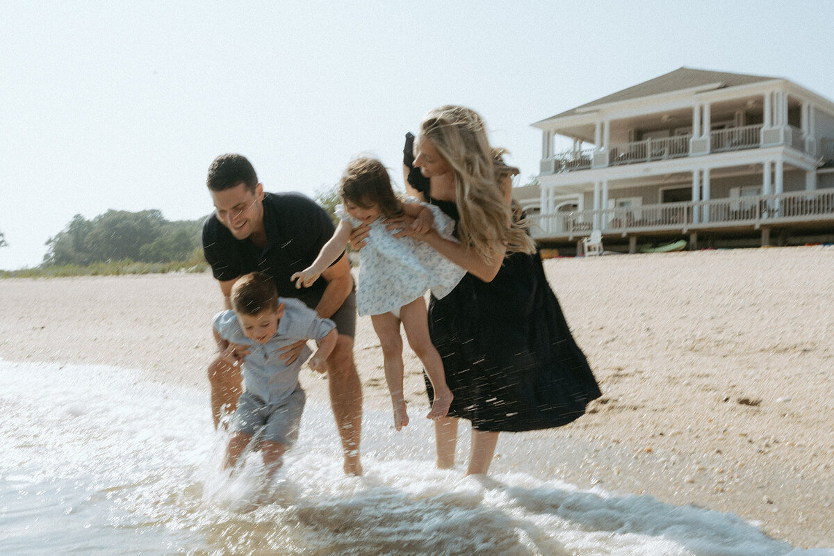 parents hold kids above water during family photoshoot at the beach captured by NYC family photographer Elsie Goodman
