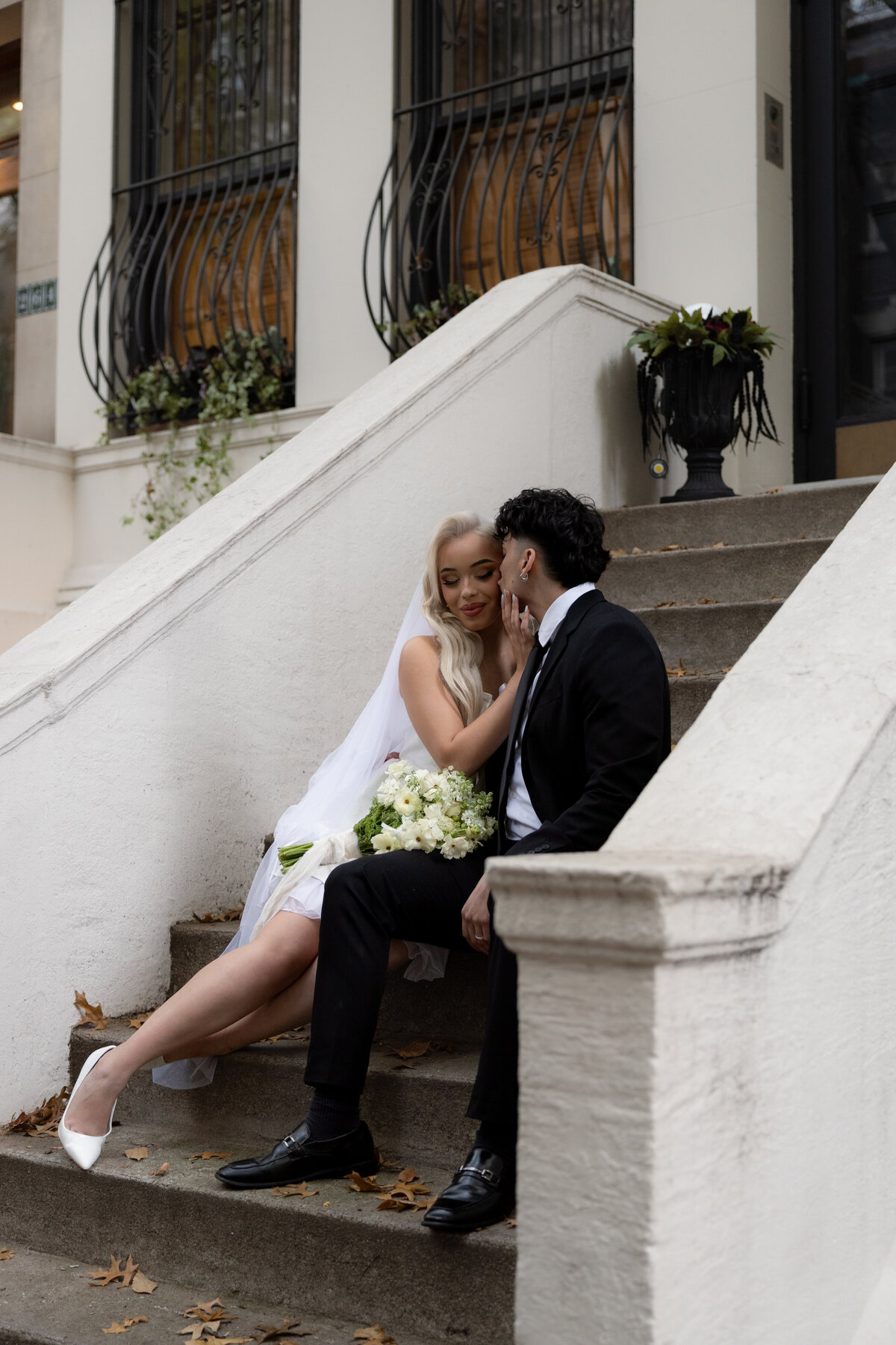 Elopement couple sitting on the steps of a brownstone in New York City.