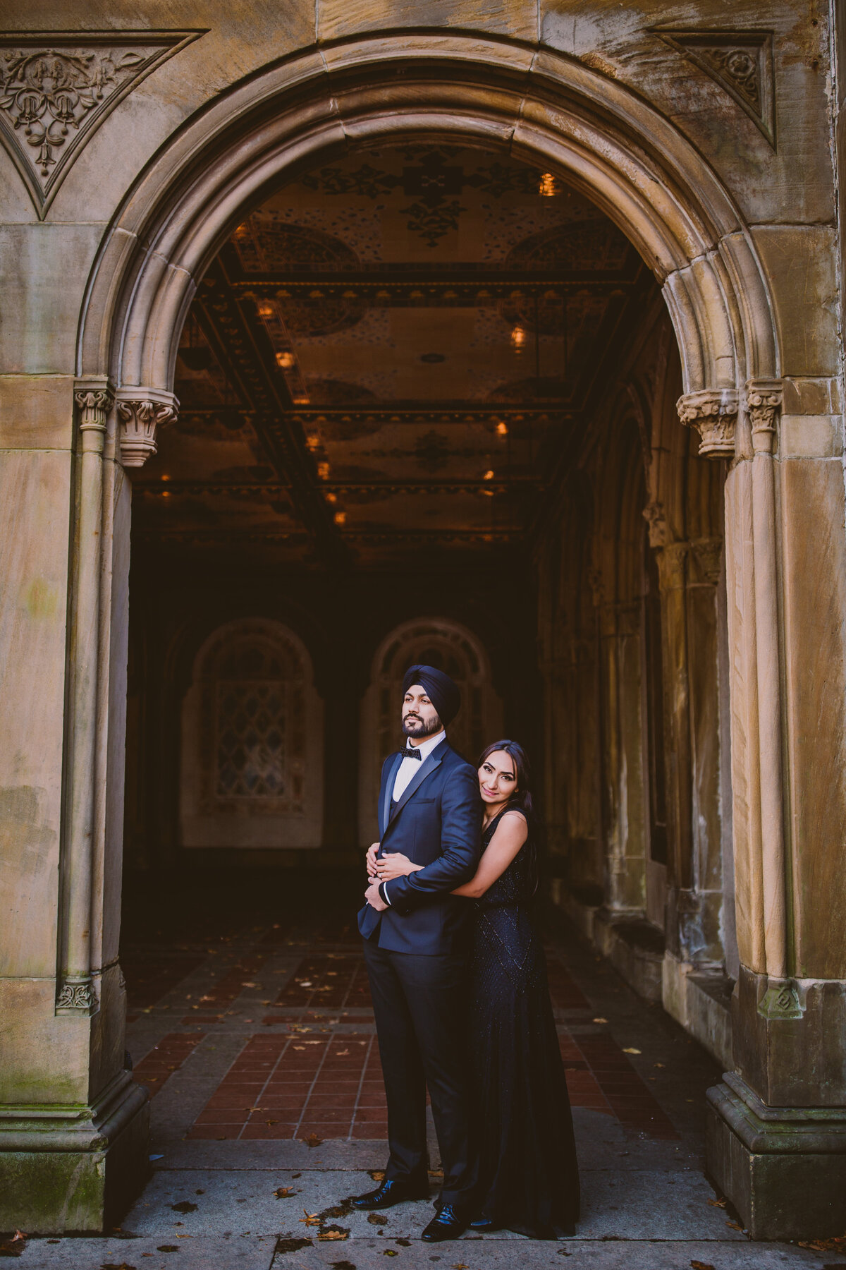 A couple in formal black clothing sharing a moment under the arch at the bethesda terrace arcade inside central park in manhattan nyc