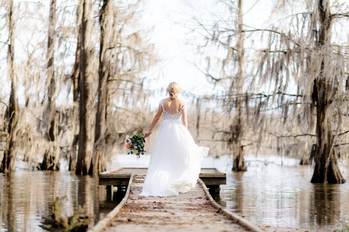 outdoor wedding photos of bride on a dock running towards the lake and away from the camera photographed by Little Rock wedding photographer