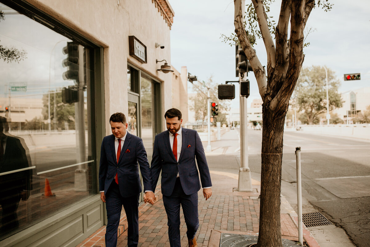 same sex couple walking downtown in Albuquerque in their wedding suits