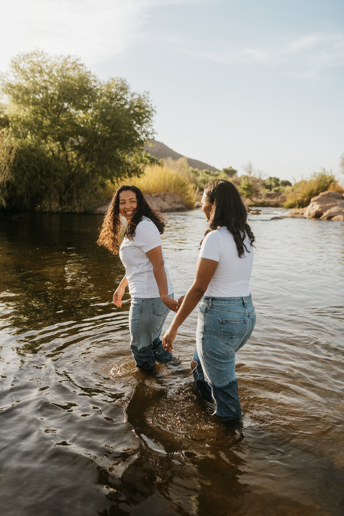 A couple holding hands and walking in the shallow waters of a lake together 