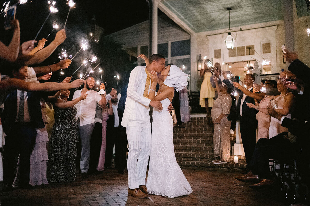 The bride and groom, wearing traditional African clothing, is kissing as the guests watch in Montage at Palmetto Bluff.