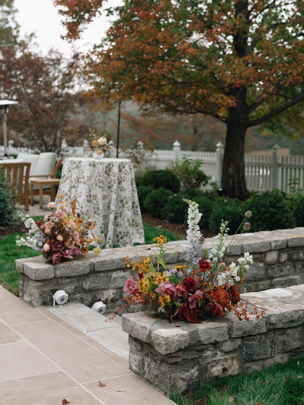 Sculptural ikebana and meadow arrangements decorate the cocktail hour for private estate wedding in Tennessee hills.Clear top tent build out for fall wedding reception in Tennessee hills.  Trailing bar arrangements and floral meadow centerpieces for autumnal wedding reception. Orchids, bittersweet berries, butterfly ranunculus, and tulips are highlighted. Artistic fall color palette in copper, gold, ruby, lavender, and rust. Design by Rosemary & Finch Floral Design in Nashville, TN.