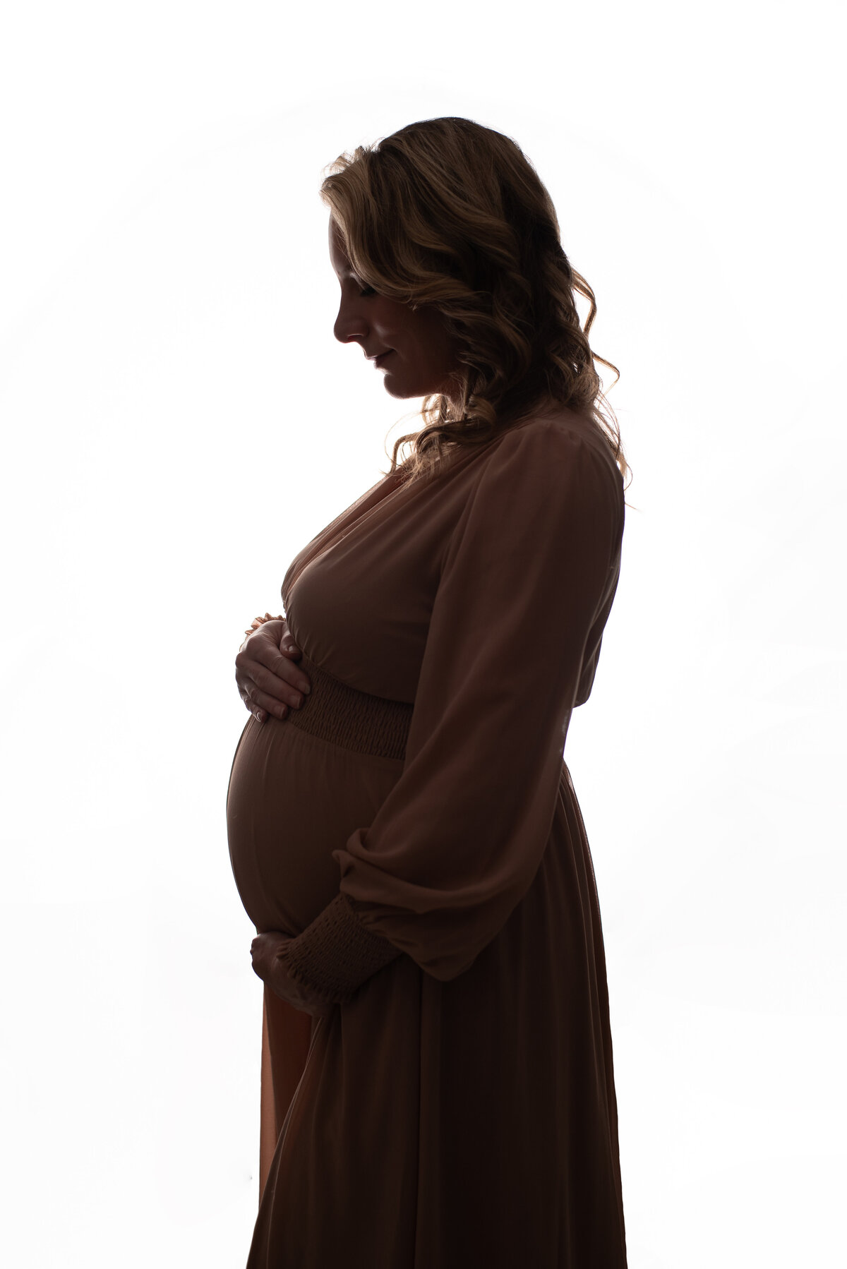 maternity silhouette picture at marietta ga maternity photography studio with pregnant woman standing against white backdrop showing side shot of tummy