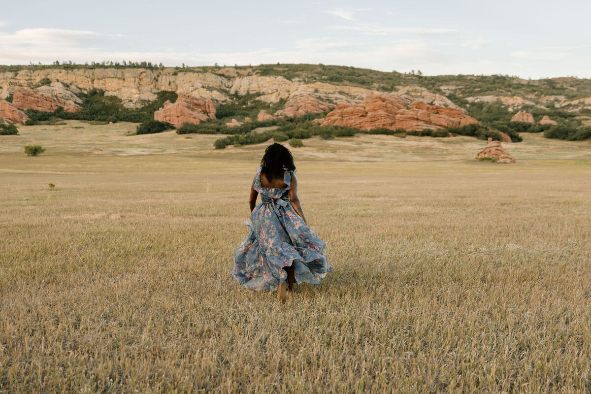 Woman running through a scenic field near Denver with Rock formations