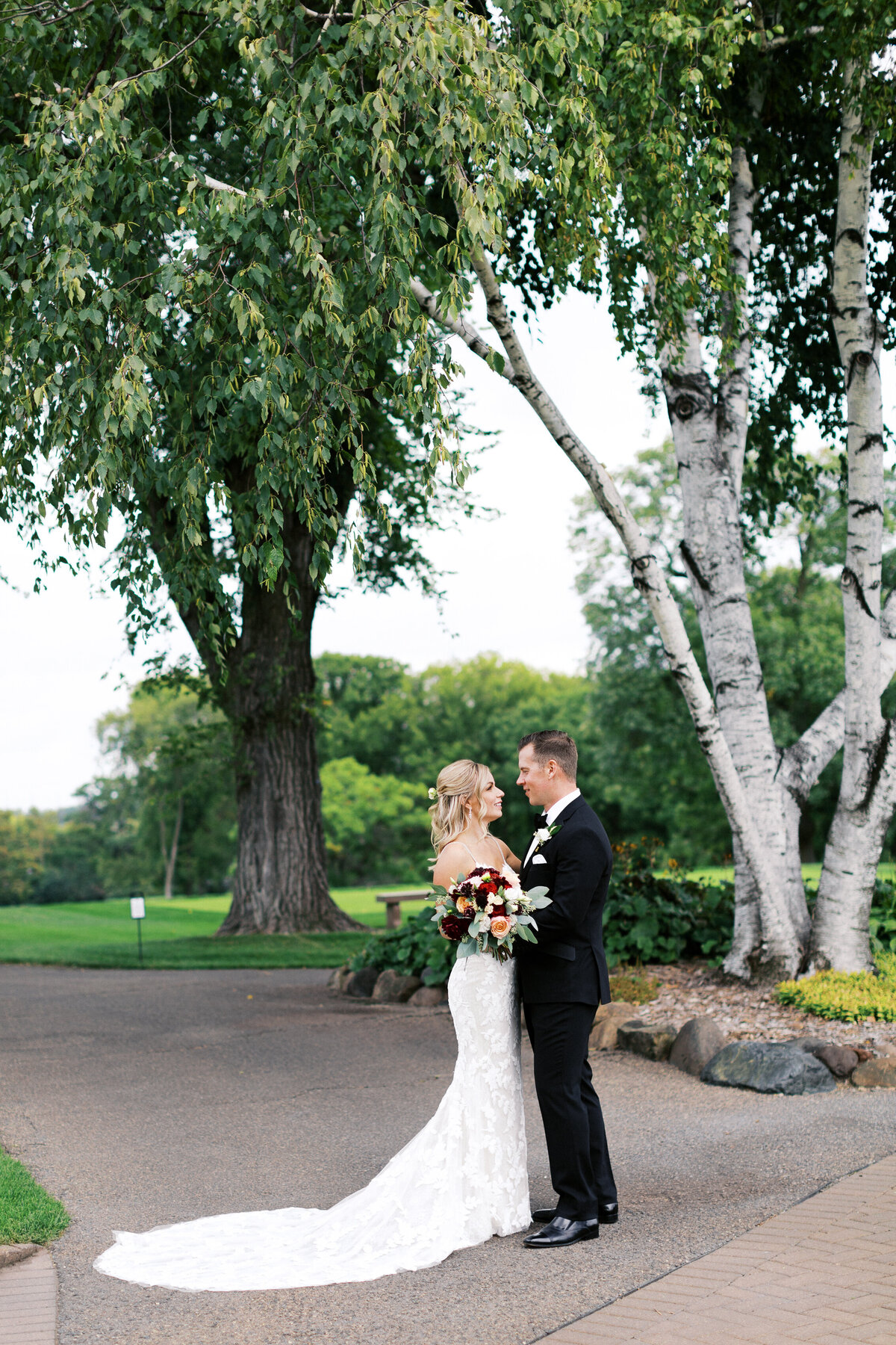 Bride and Groom standing close to each other under the willow tree and looking at each other's eyes at Minneapolis Golf Club wedding. 