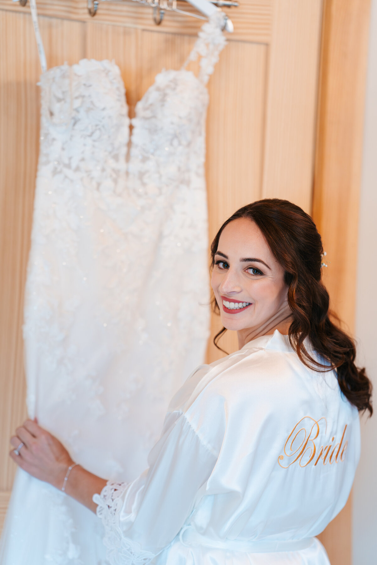 Bride putting on earrings in soft window light before her New England wedding