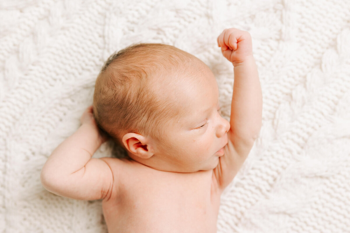 Newborn baby boy raising his fist during his in-home newborn session in augusta ga