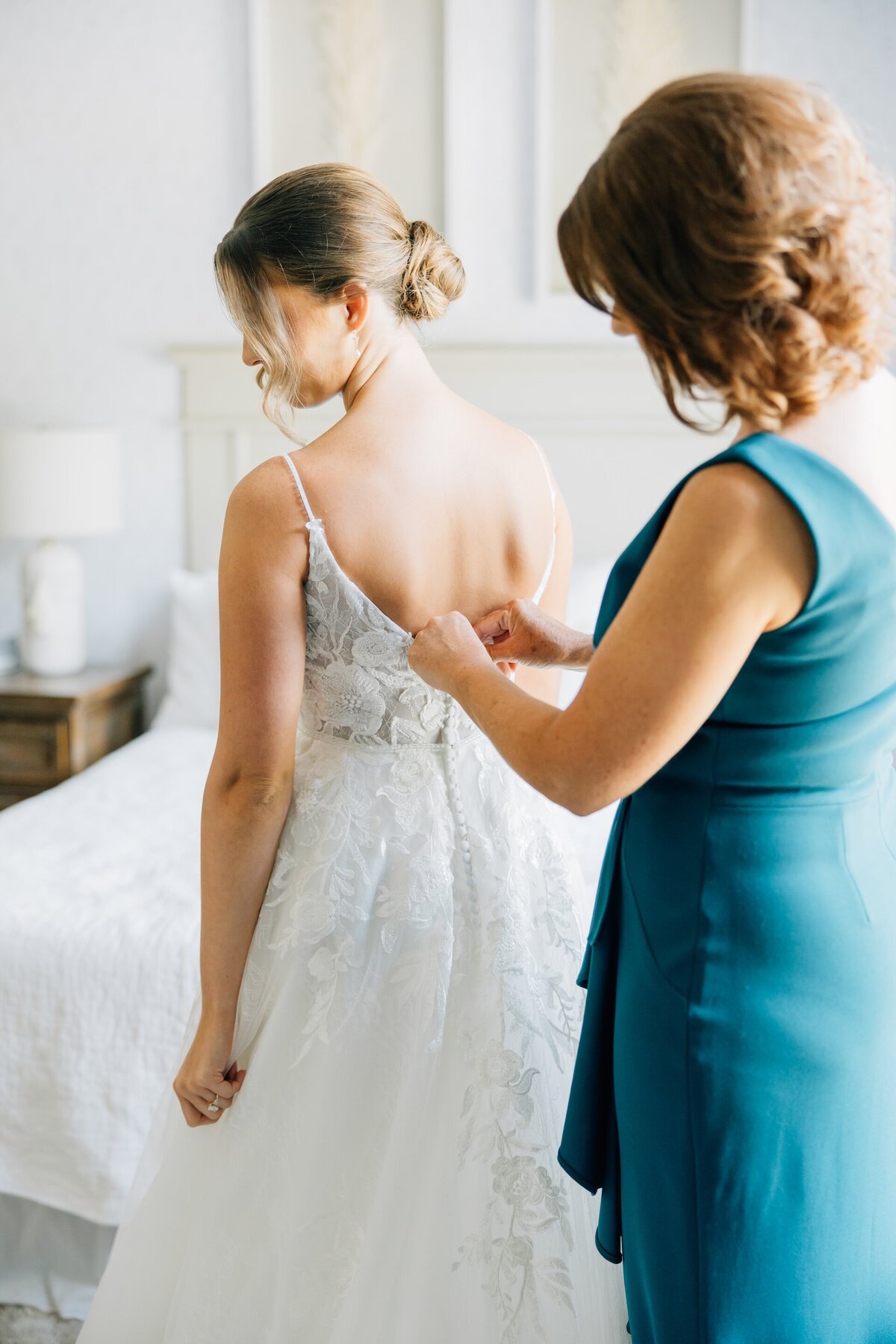 mother of the bride helping button her daughter's wedding dress