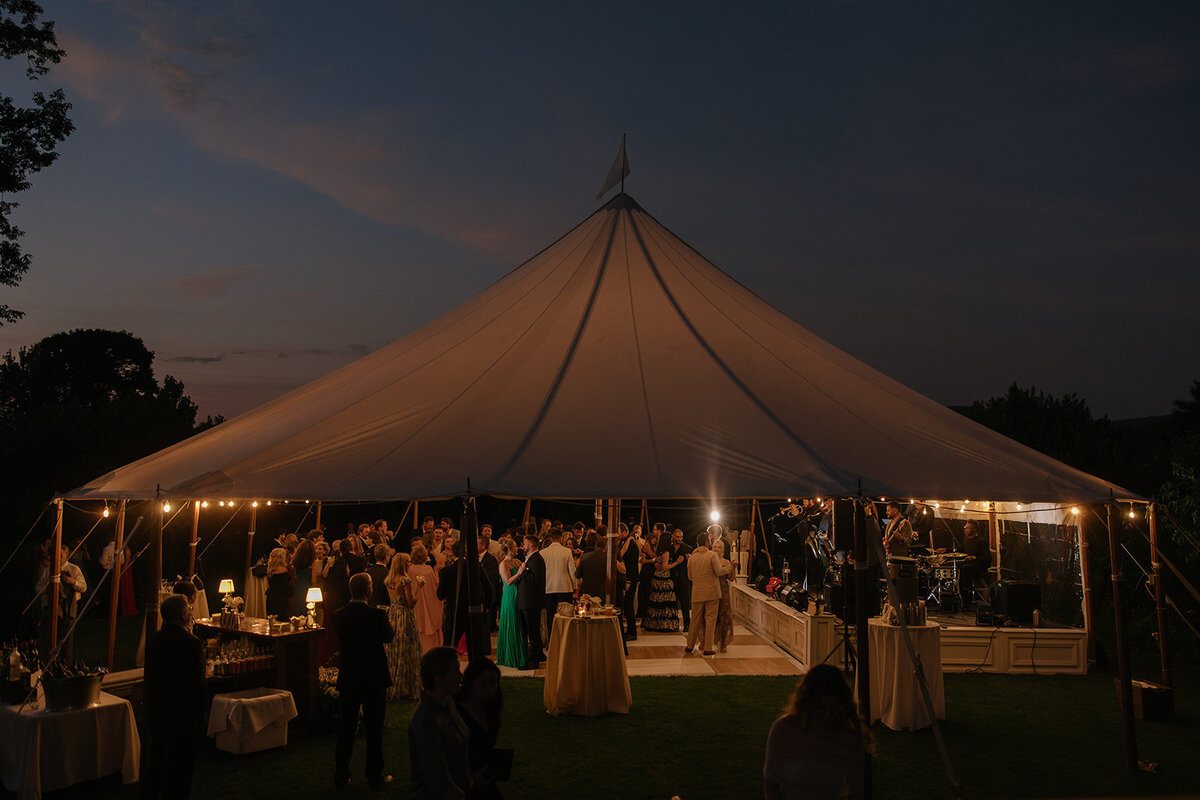 Sail cloth tented wedding reception as dusk with guests mingling underneath.