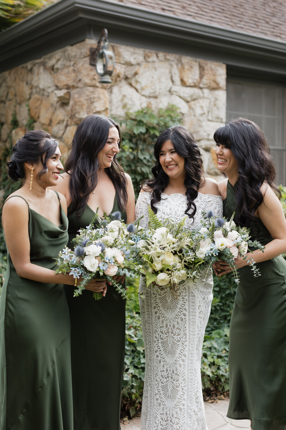 The bride and her bridesmaids, dressed in elegant green gowns, share a joyful moment at a picturesque Napa Valley wedding.