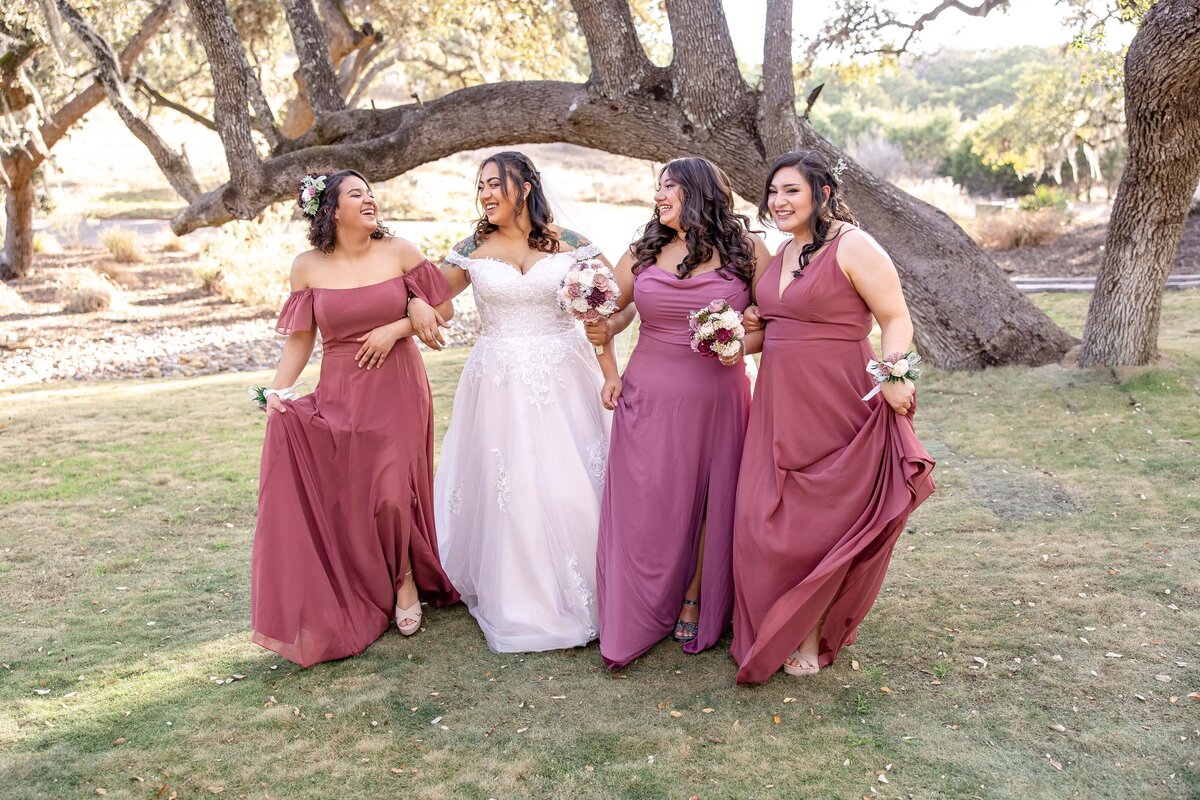 bride walks with 3 bridesmaids in coordinating dresses at Hayes Hollow at Hidden Falls in Spring Branch Texas