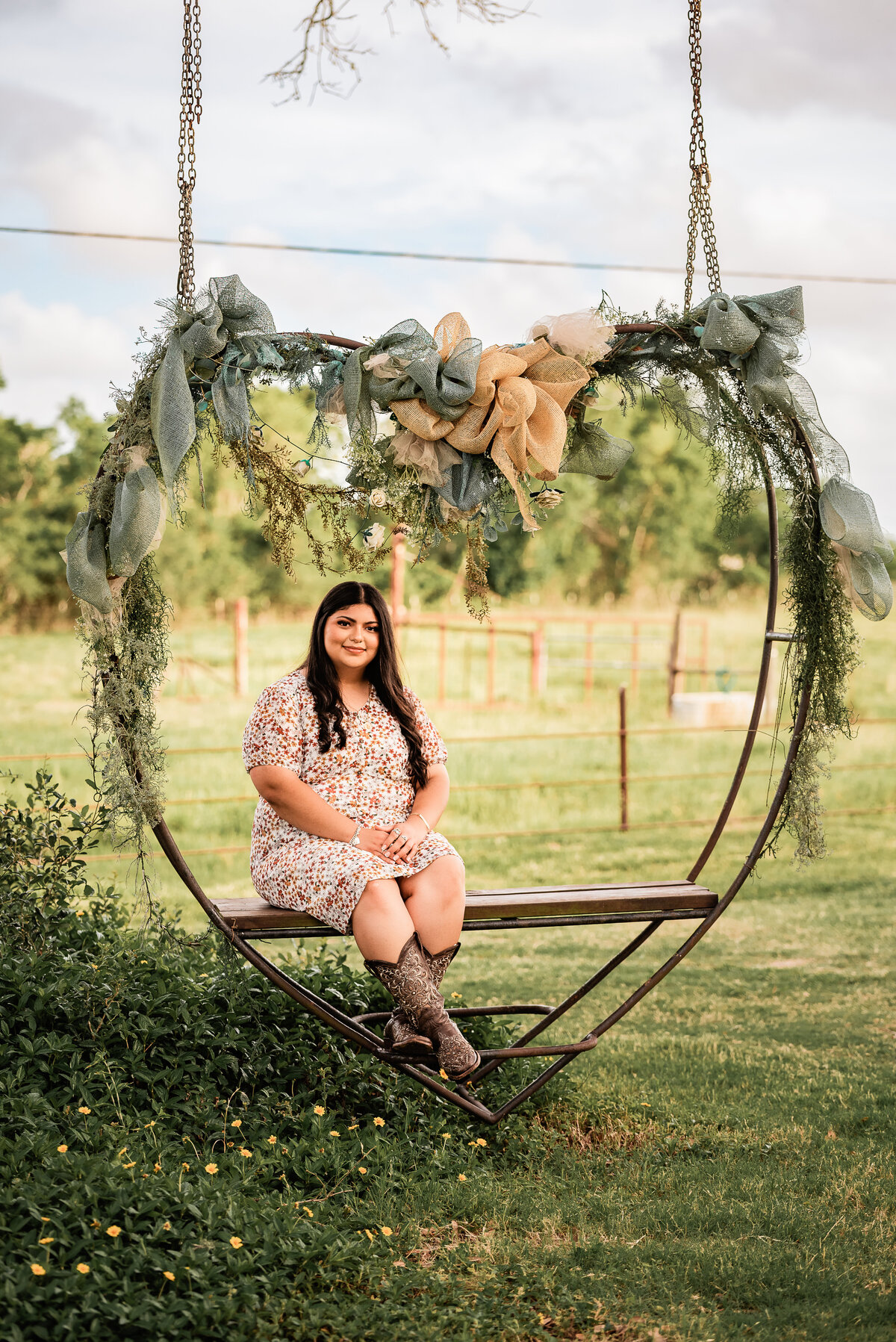 A Galveston county senior sits in a heart shaped metal swing decorated with greenery.