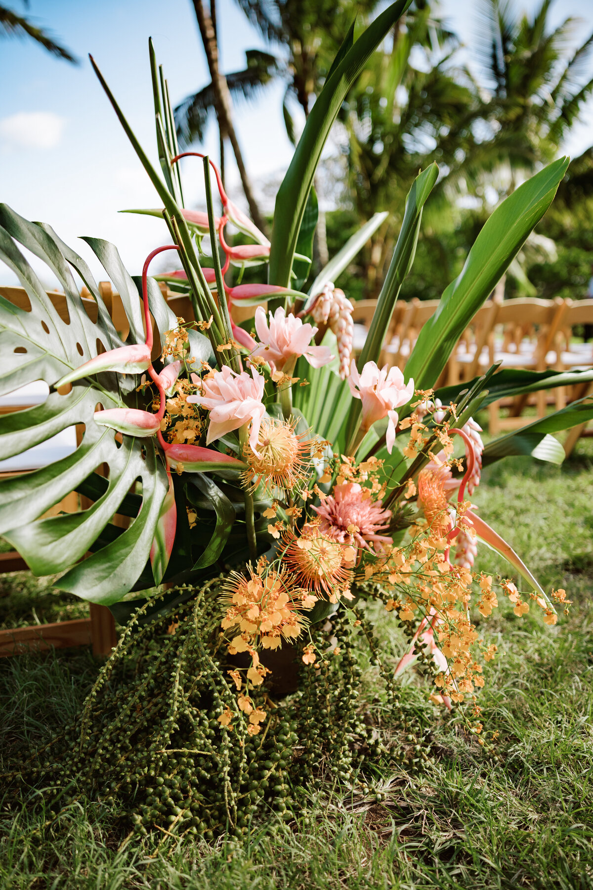 Lush, overflowing tropical flower arrangement lining the aisle, captured in a detailed film photo with a documentary approach — by Kate Winters Photography.