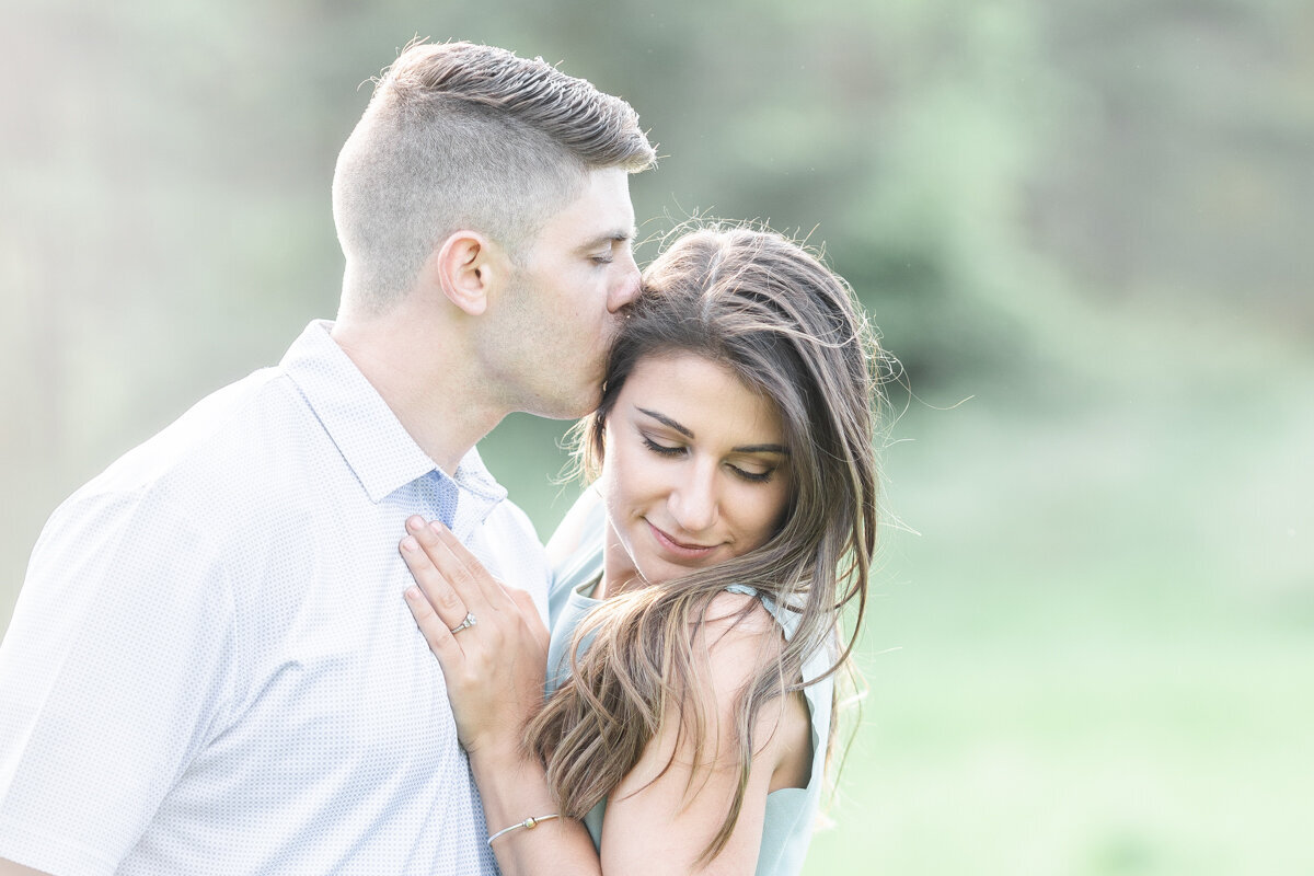 Man kissing his fiance's head  during their engagement session in Binghamton, NY