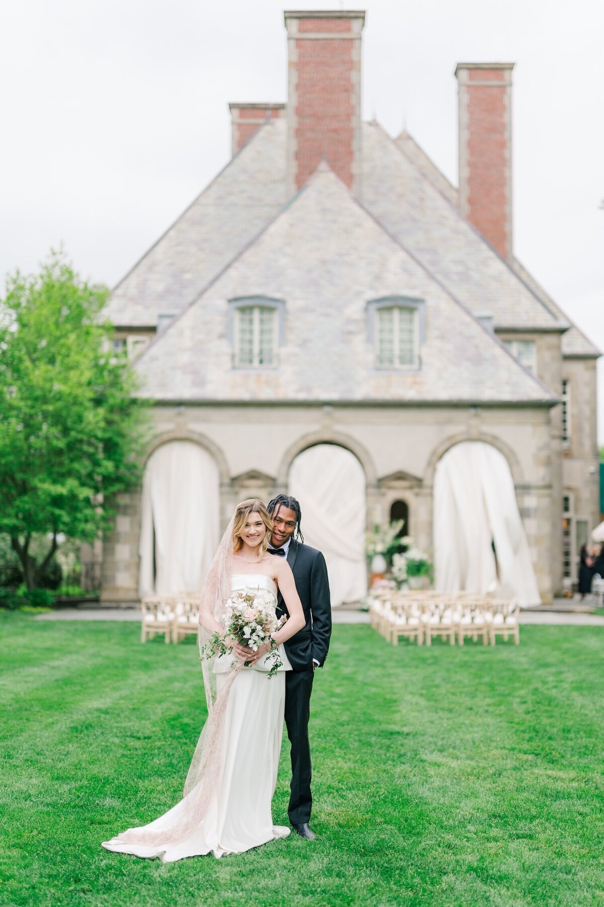 A bride standing in front of her groom with Glen Manor House in the background