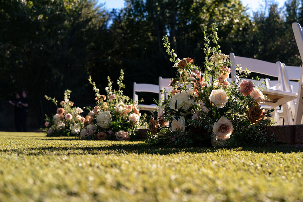 Elegant floral arrangements marking the aisle, featuring roses and greenery.