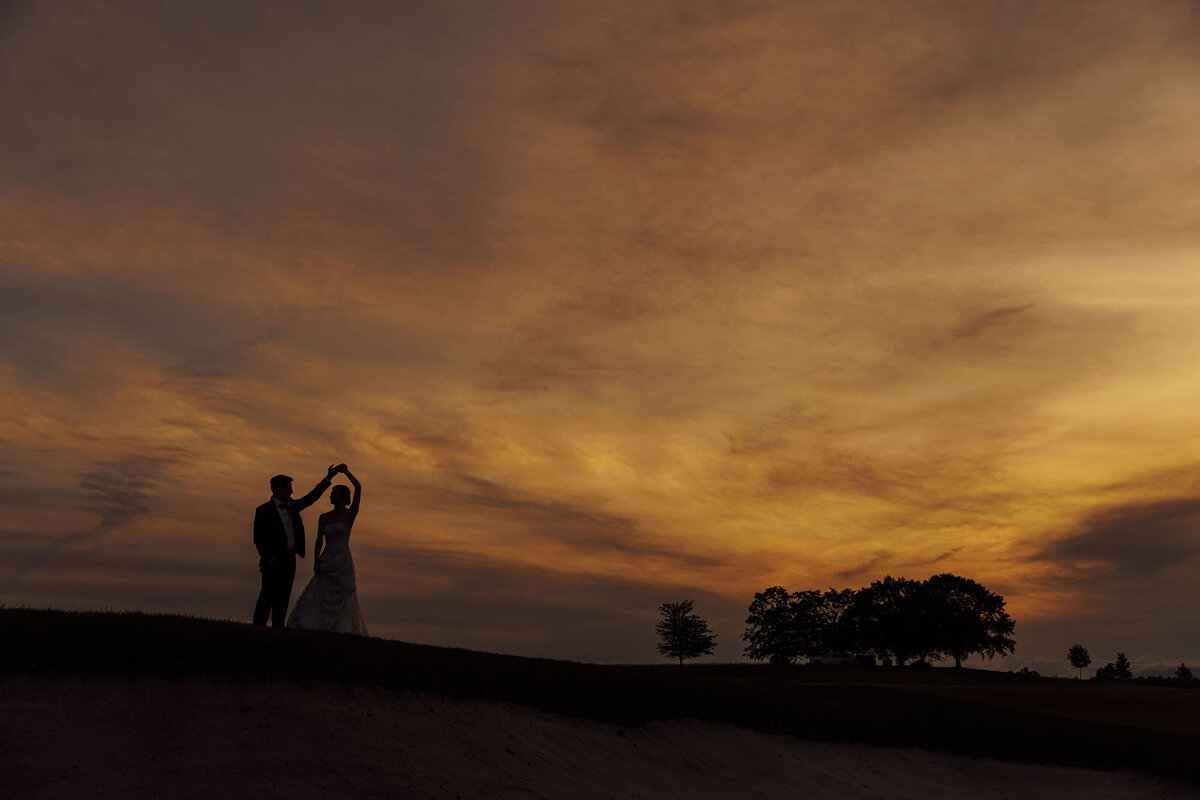 Trump National Golf Club | Groom twirling bride on green at sunset during wedding | Bedminster, New Jersey