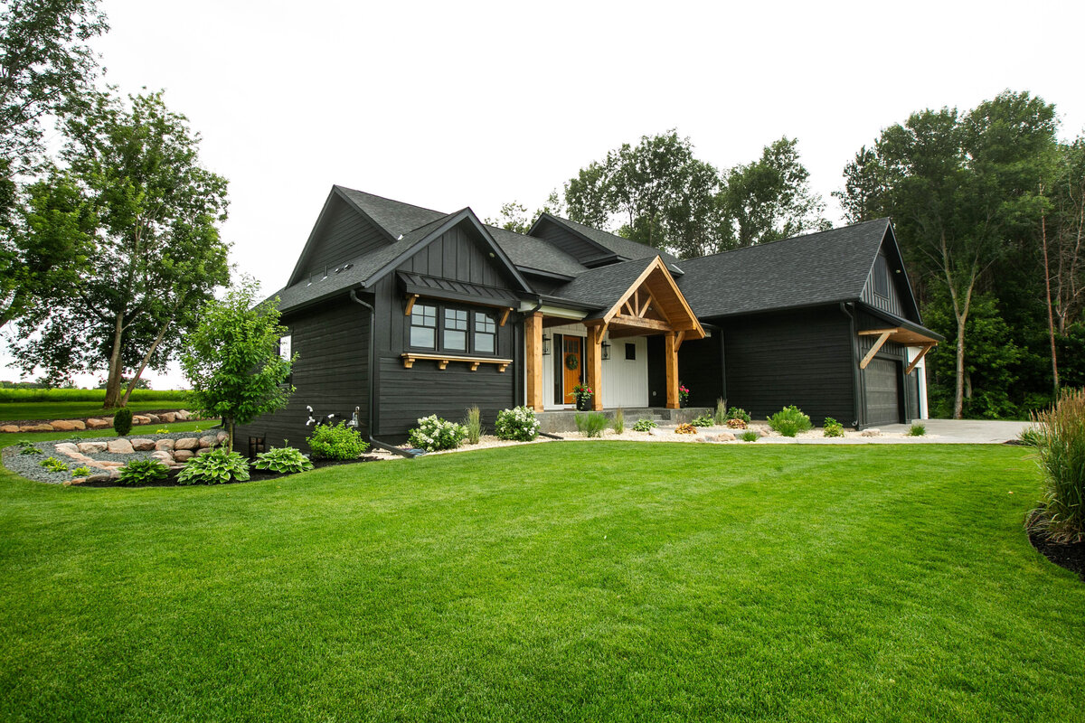 Exterior view of custom home in Otsego, Minnesota with modern wood details and front porch built by Cornerstone Custom Builds
