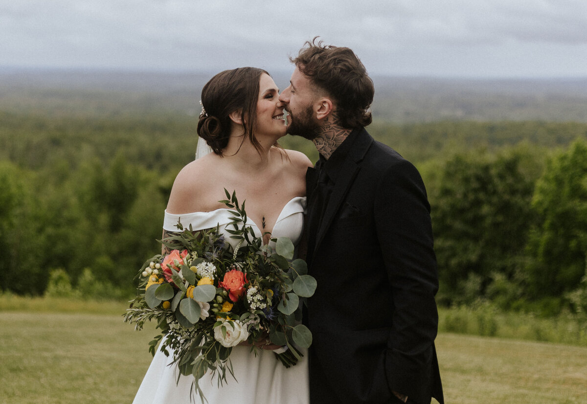 Couple kissing during their portrait photos outside on a grey cloudy day.