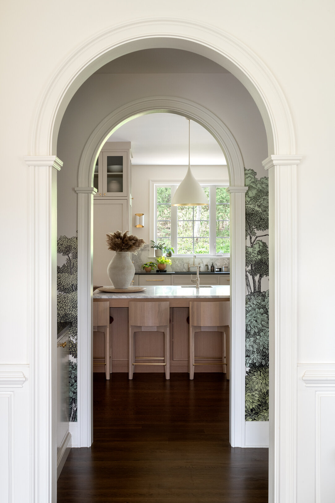 off white archway into kitchen with light wood island