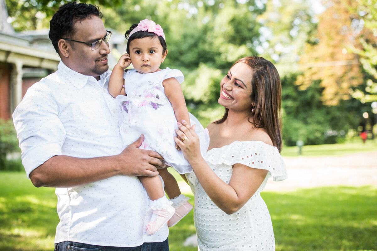 Two parents smiling as they hold their baby
