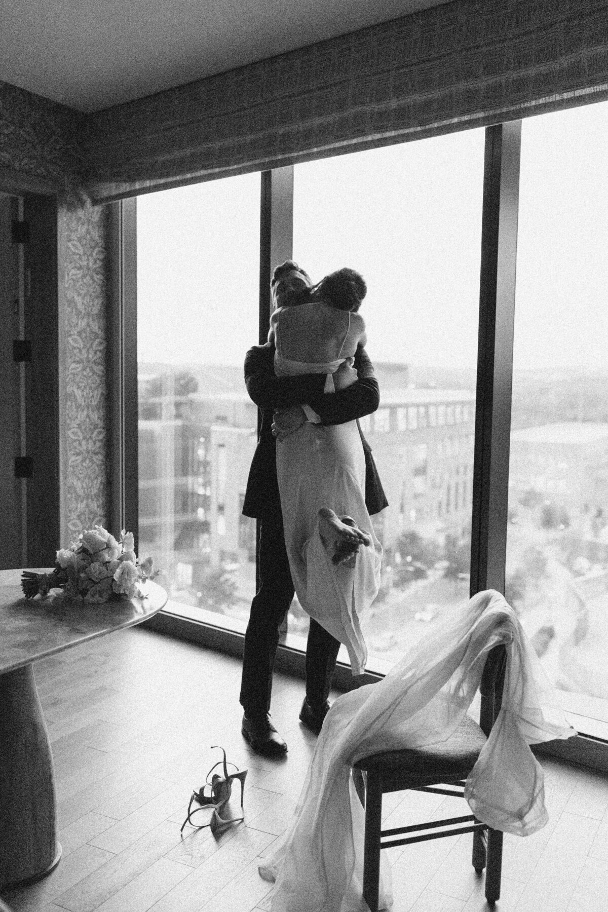Groom holding bride up by open windows overlooking the city of Austin